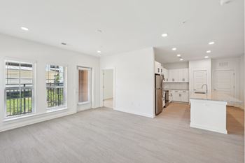 A spacious kitchen and living room with white cabinetry and a large window.